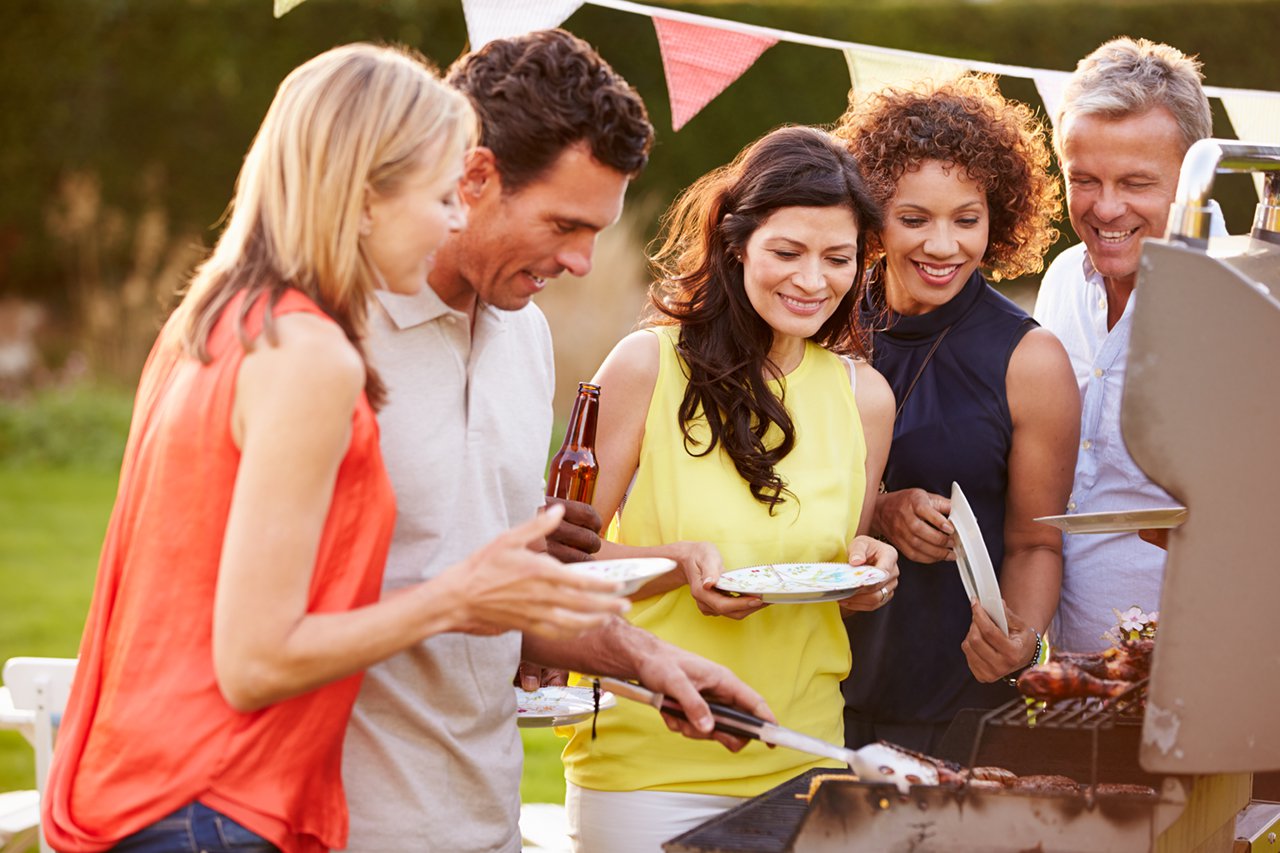 mature friends enjoying outdoor summer barbeque in garden
